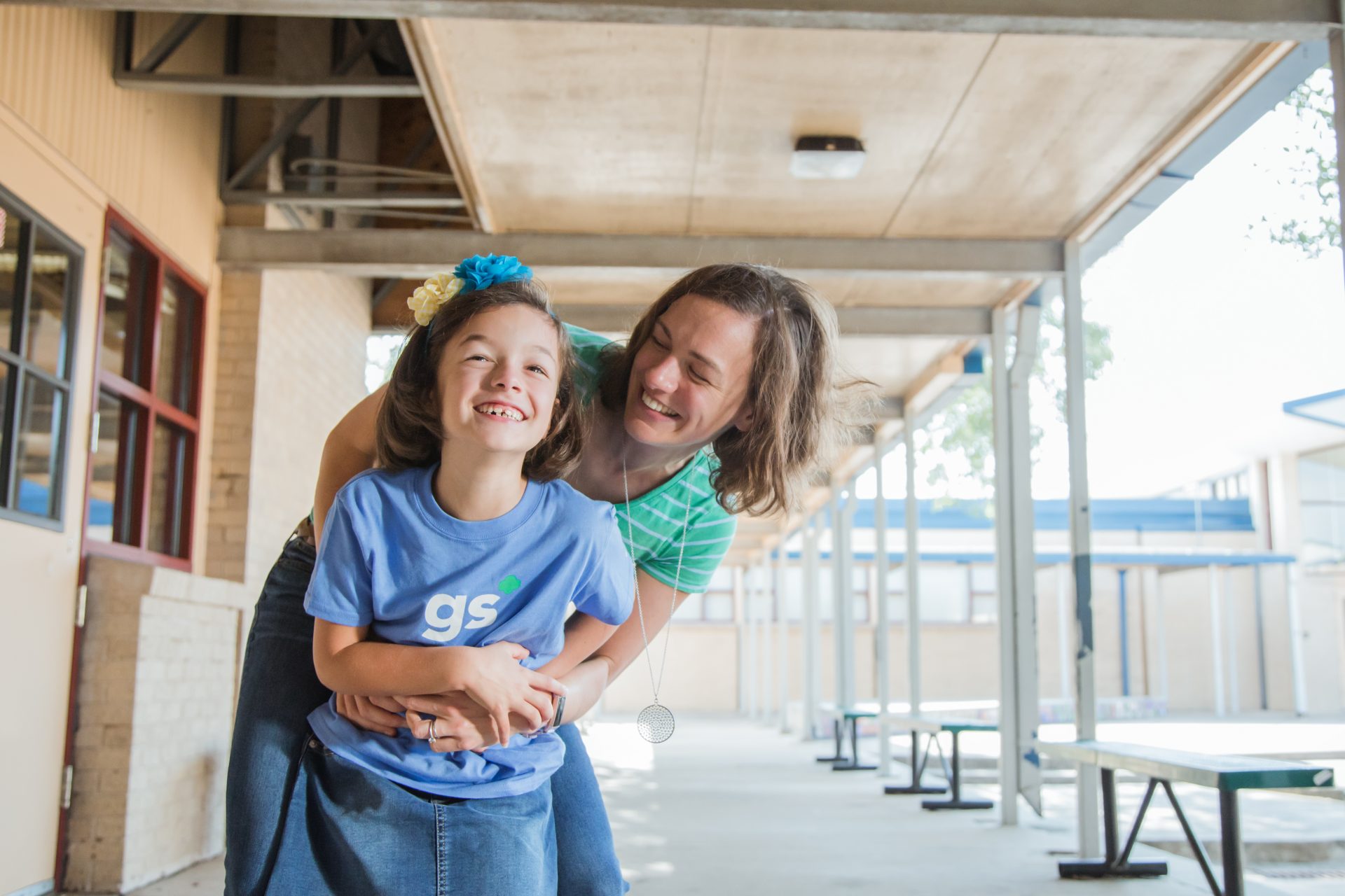 mom hugging her daughter outside a school yard 