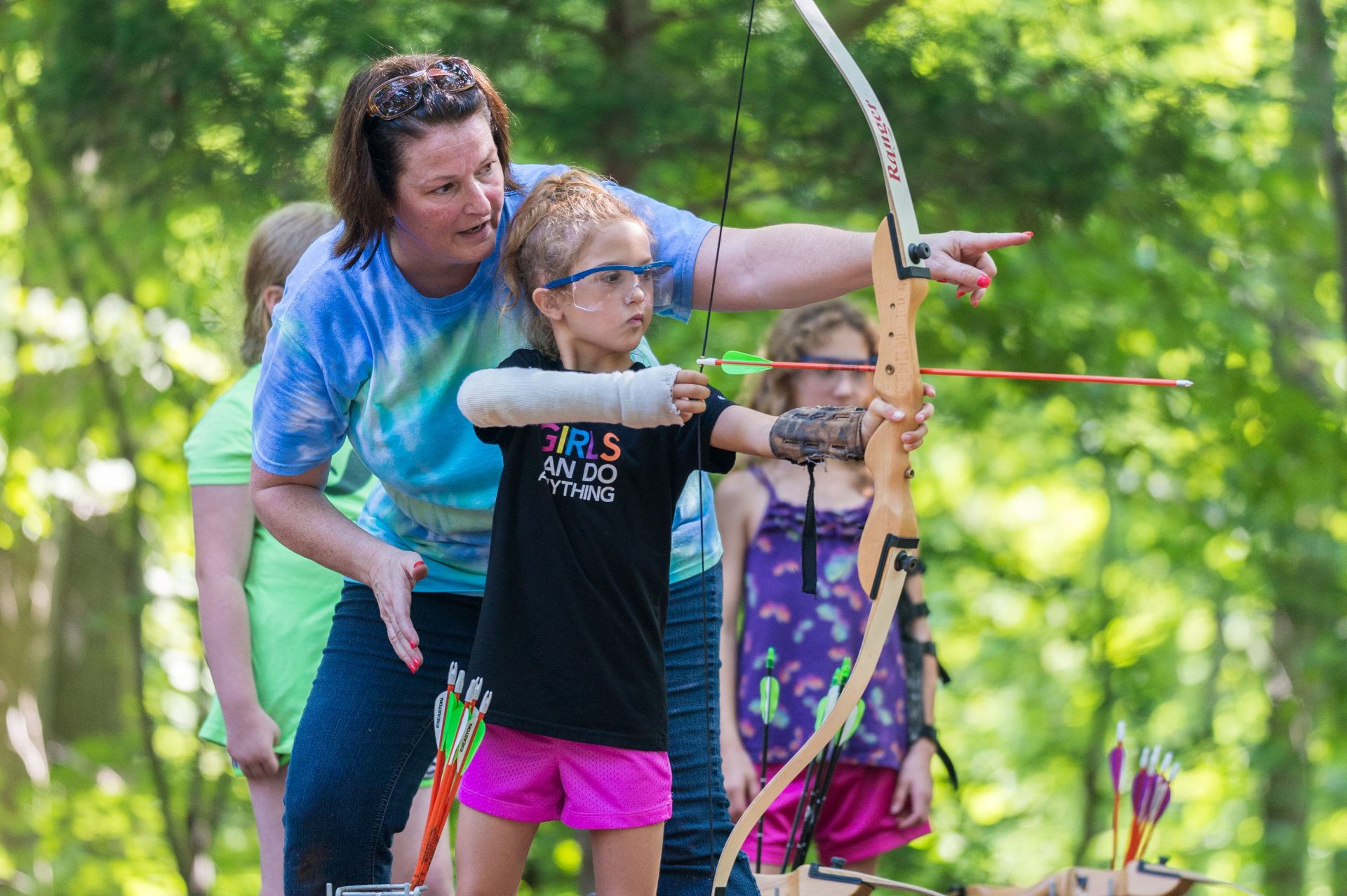 training showing a young girl how to do archery